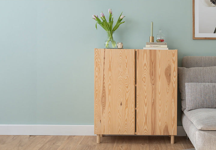 Kommode mit Dekoration vor blauer Wand im Wohnzimmer